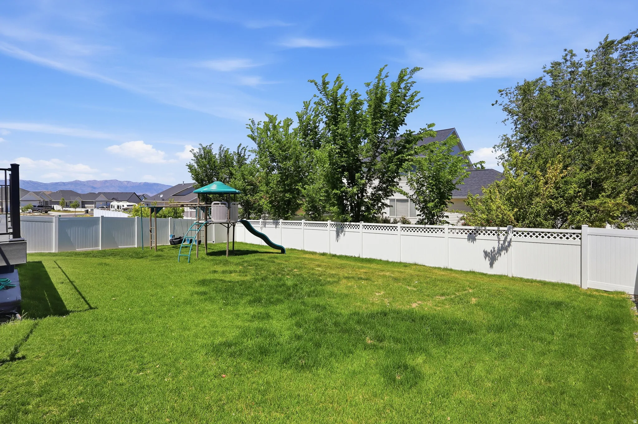 Expansive green lawn surrounded by a white vinyl privacy fence