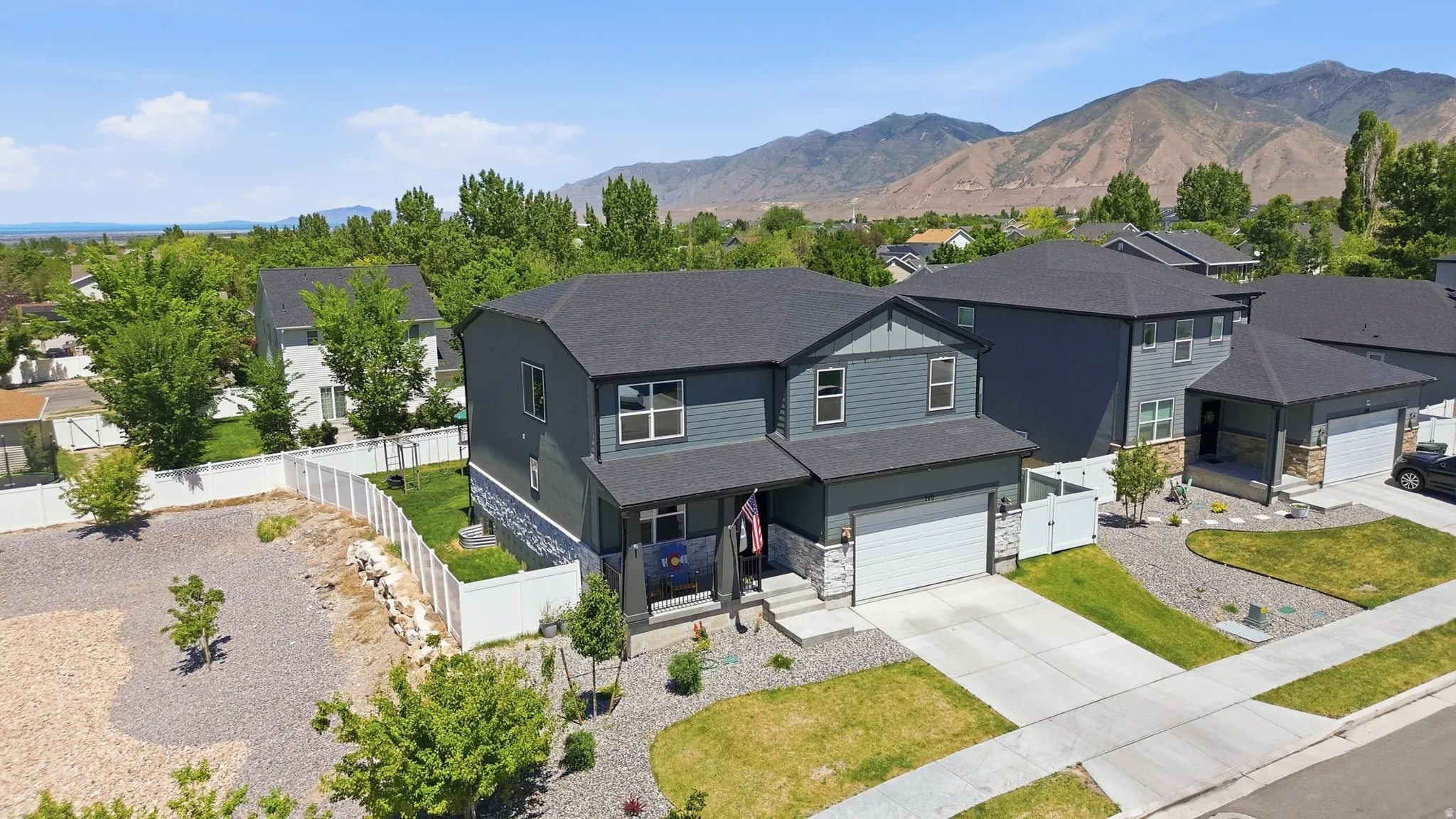 Contemporary two-story residence featuring a gray exterior with stone accents and a covered front porch