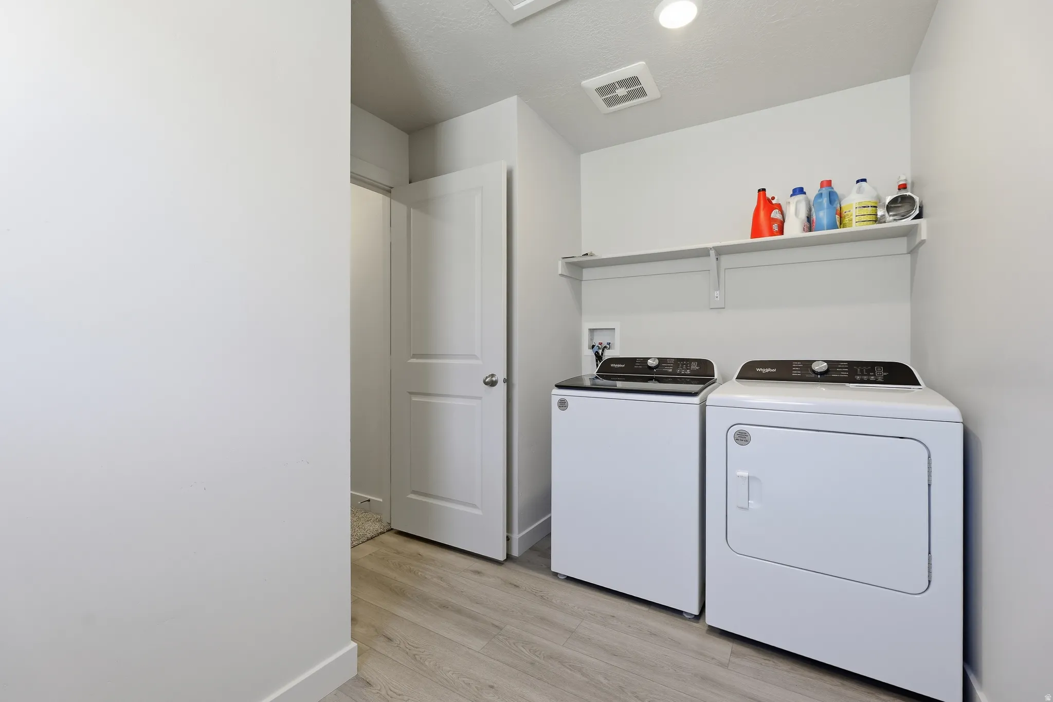 Laundry area featuring a built-in shelf, wood-finish flooring, white walls, and a white interior door