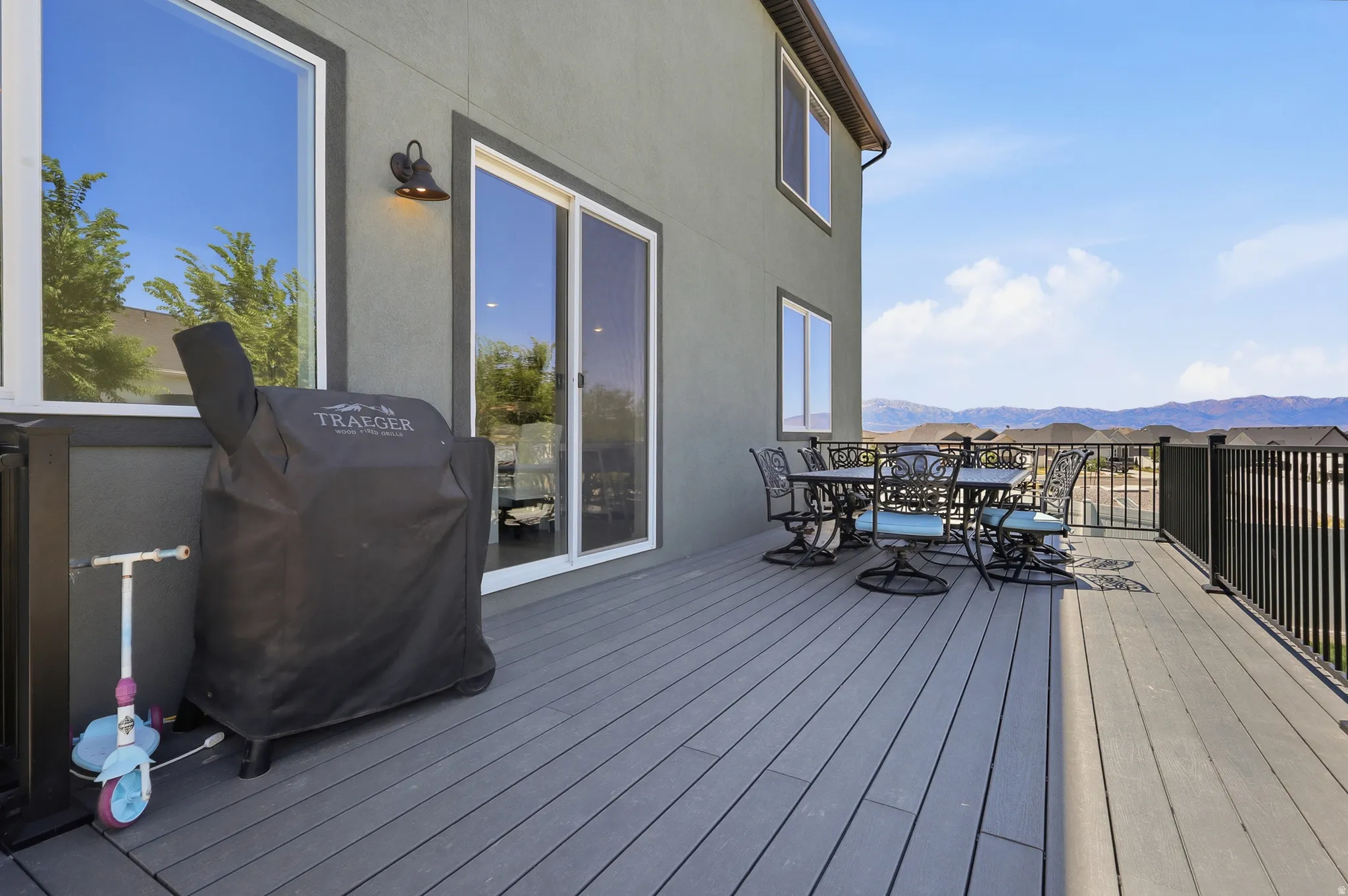 Spacious outdoor deck featuring composite decking, a black metal railing, and direct access to interior spaces via a sliding glass door