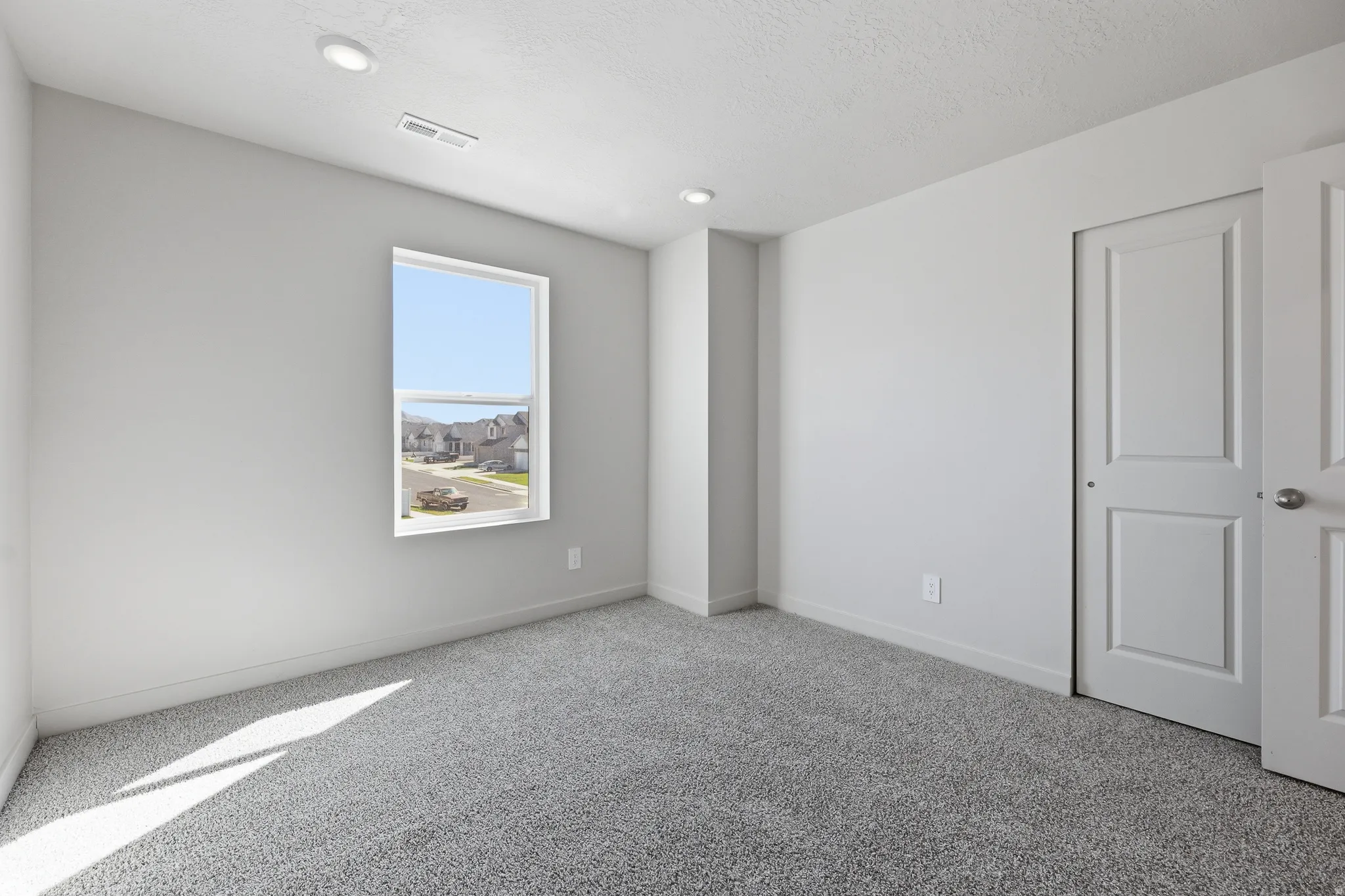 Wall-to-wall carpeting with recessed lighting, a single window, and a paneled closet door