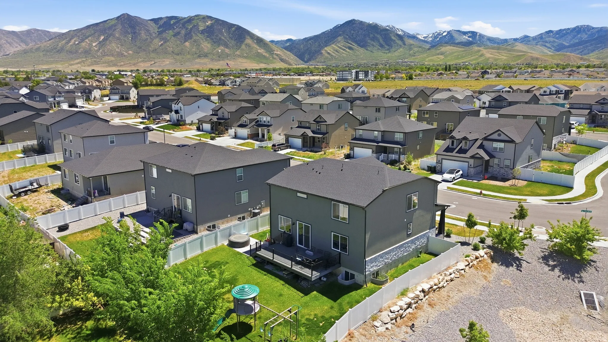 Residential neighborhood featuring uniformly styled homes with dark roofs and light-colored fencing