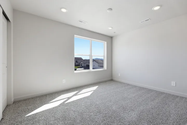Spacious room featuring a large window, recessed lighting, and grey carpet flooring