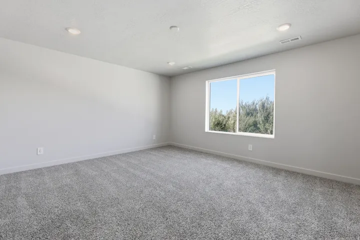 Recessed lighting, large window, light gray walls, gray carpeting