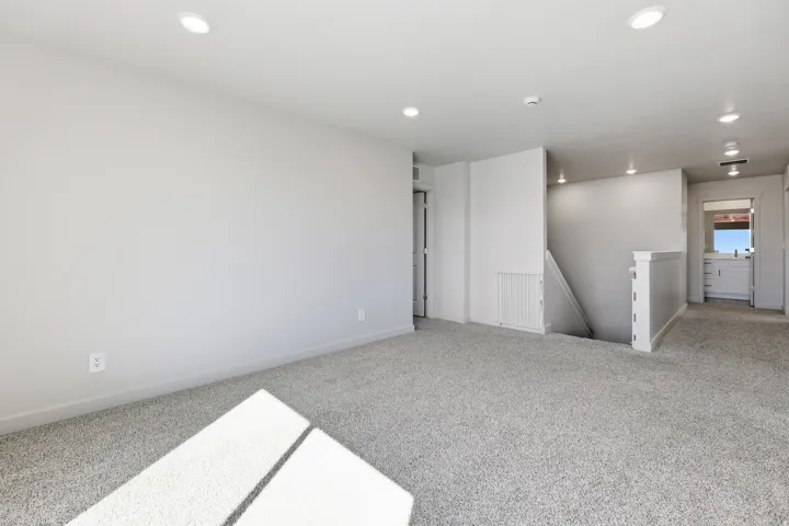 Spacious room with gray carpet flooring and recessed lighting