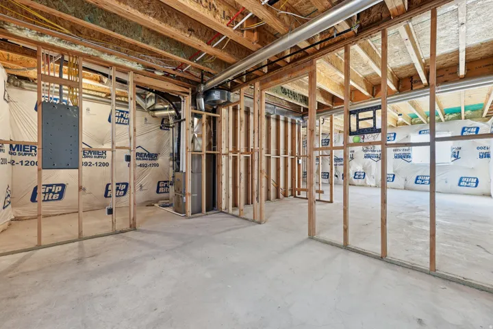 Unfinished basement with exposed wood framing, concrete flooring, visible insulation, and ductwork