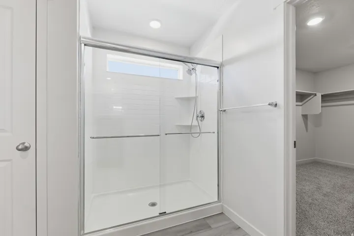 Shower enclosure with subway tile surround, integrated shelving, and a transom window