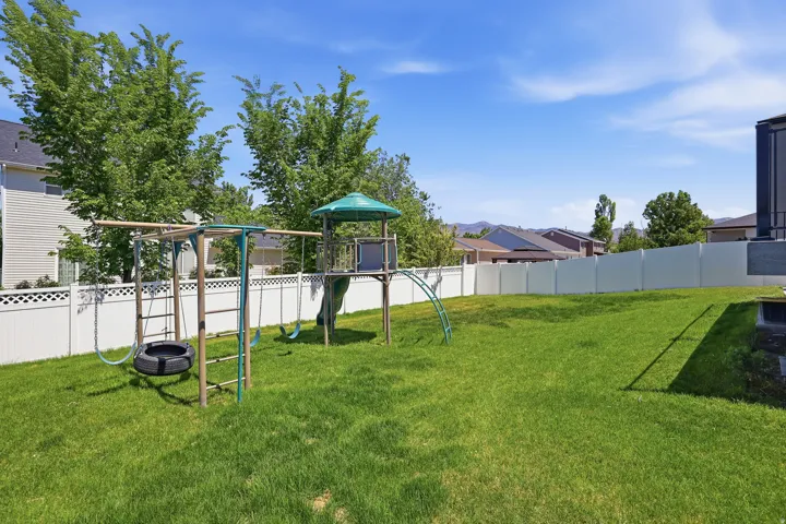 Expansive grassy backyard featuring a white privacy fence and established trees