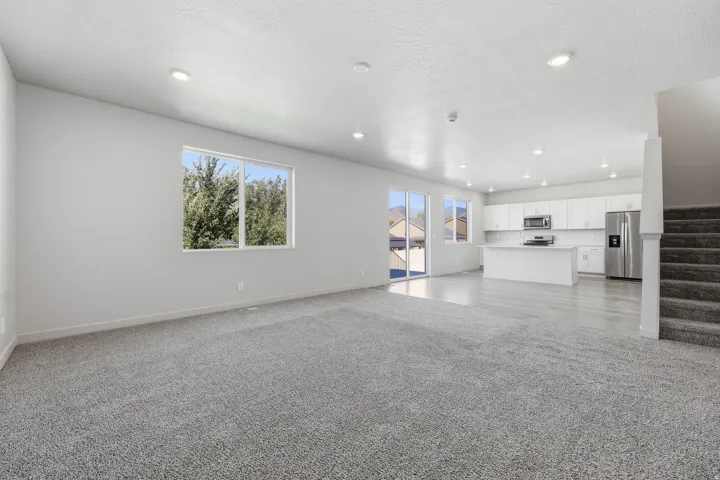 Open-concept layout featuring recessed lighting, a modern kitchen with white cabinetry, stainless steel appliances, and a central island