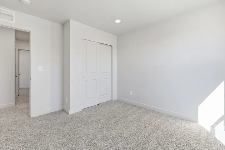 Plush gray carpeting, recessed ceiling lighting, and a sliding panel closet door