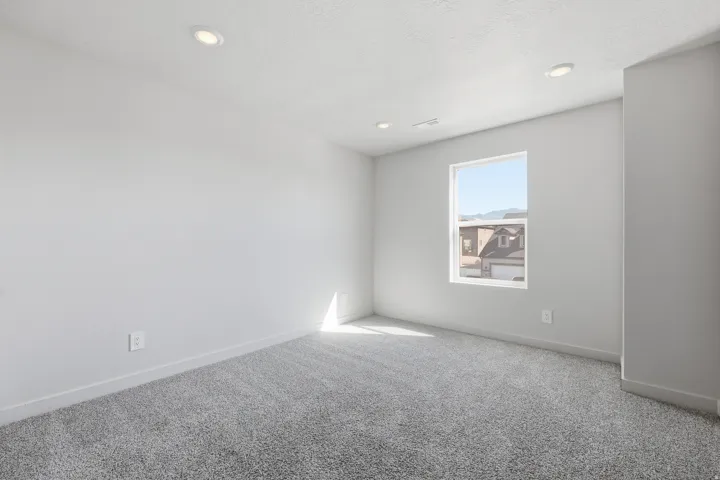 Recessed lighting fixtures, broad window, light gray wall finish, gray carpet flooring