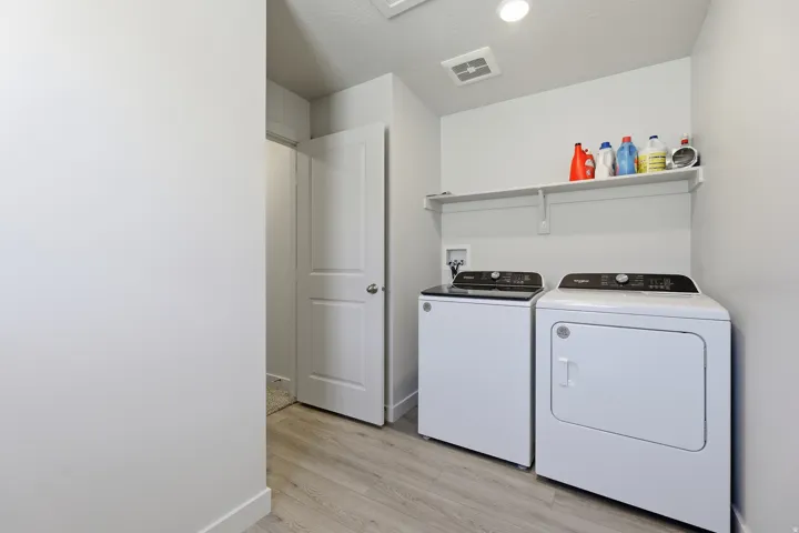 Laundry area featuring a built-in shelf, wood-finish flooring, white walls, and a white interior door