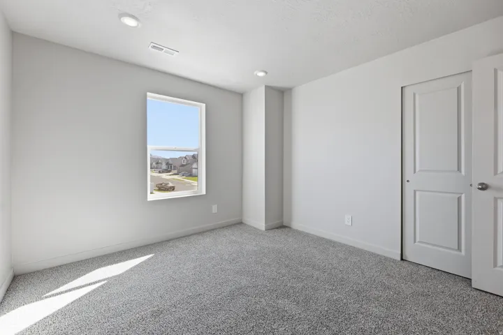 Wall-to-wall carpeting with recessed lighting, a single window, and a paneled closet door
