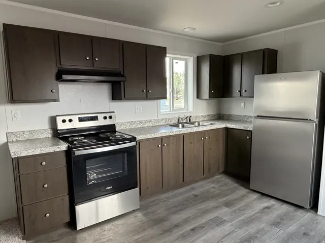 Kitchen featuring wood-finish cabinetry, light-toned countertops, and stainless steel appliances