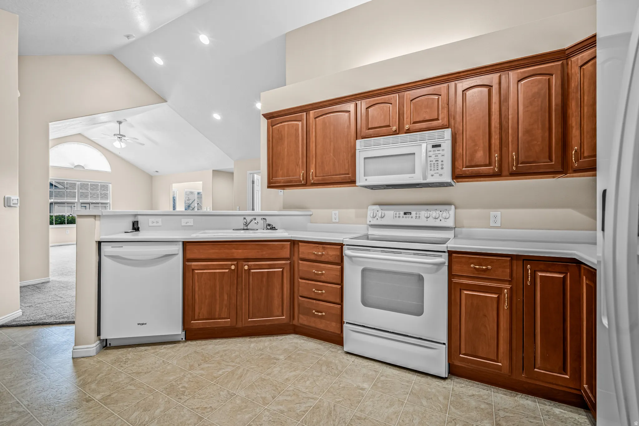 Kitchen featuring warm wood cabinetry, white appliances
