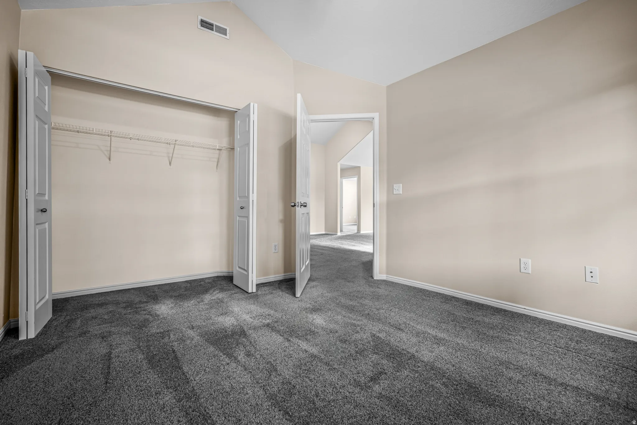 Vaulted ceiling room with neutral paint, gray carpeting, and white trim