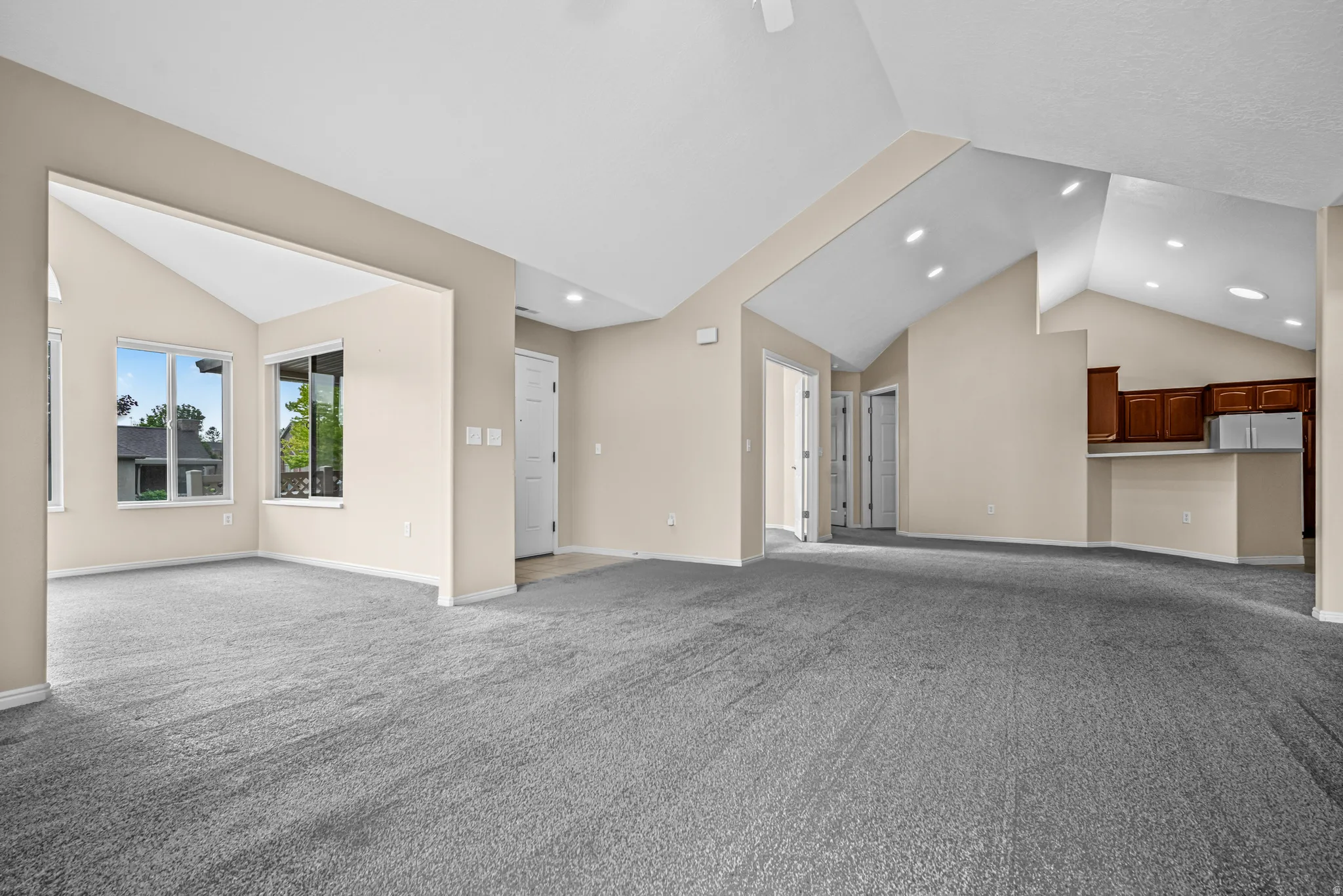 Spacious interior with vaulted ceilings, recessed lighting, and soft grey carpeting