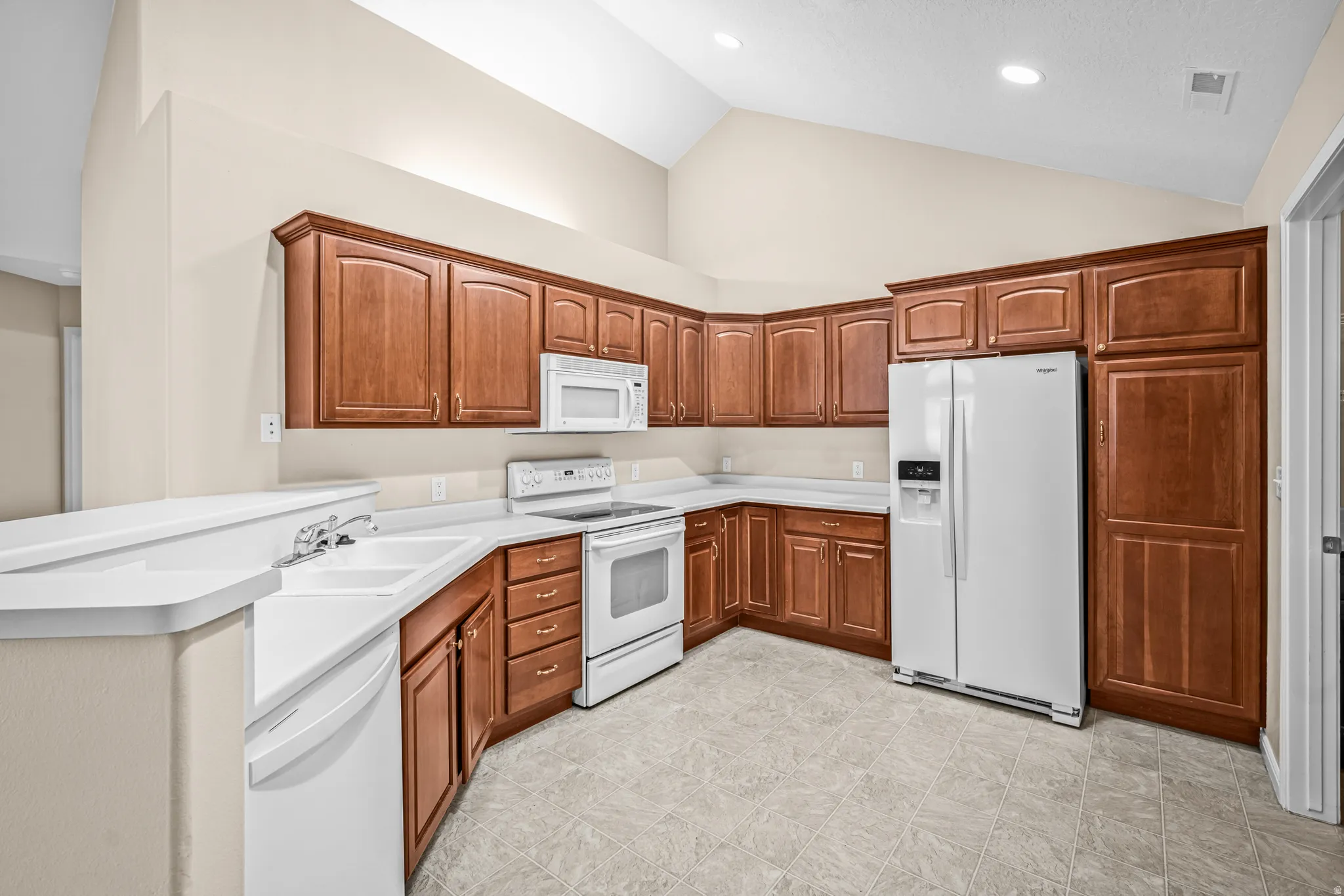 Kitchen featuring wood-finish cabinetry, white countertops, and white appliances