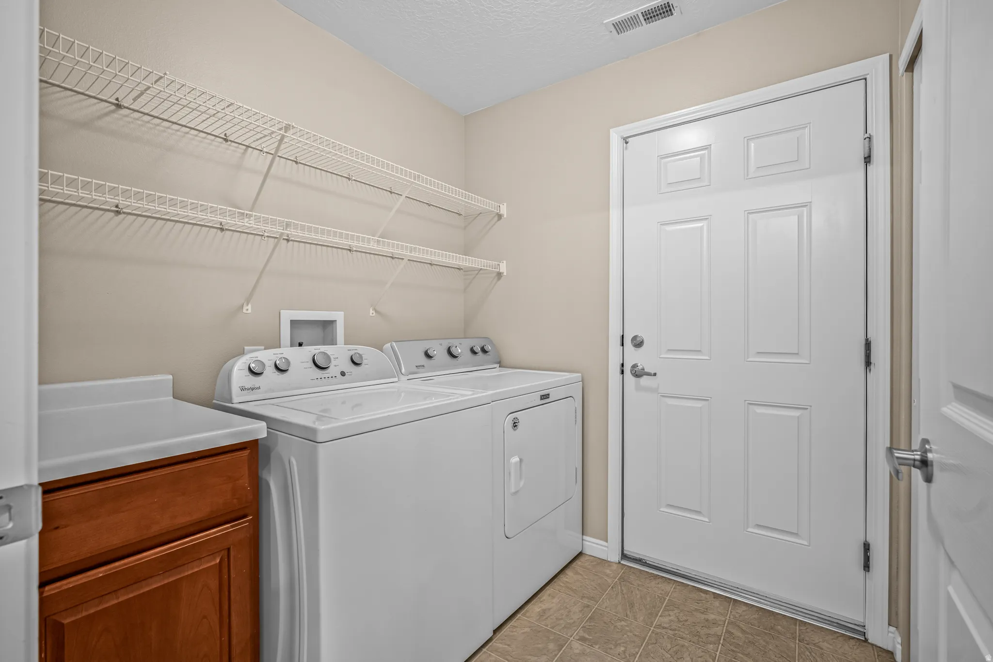 Laundry room featuring a paneled door, built-in wire shelving, and wood-finish.  Washer and dryer are included.