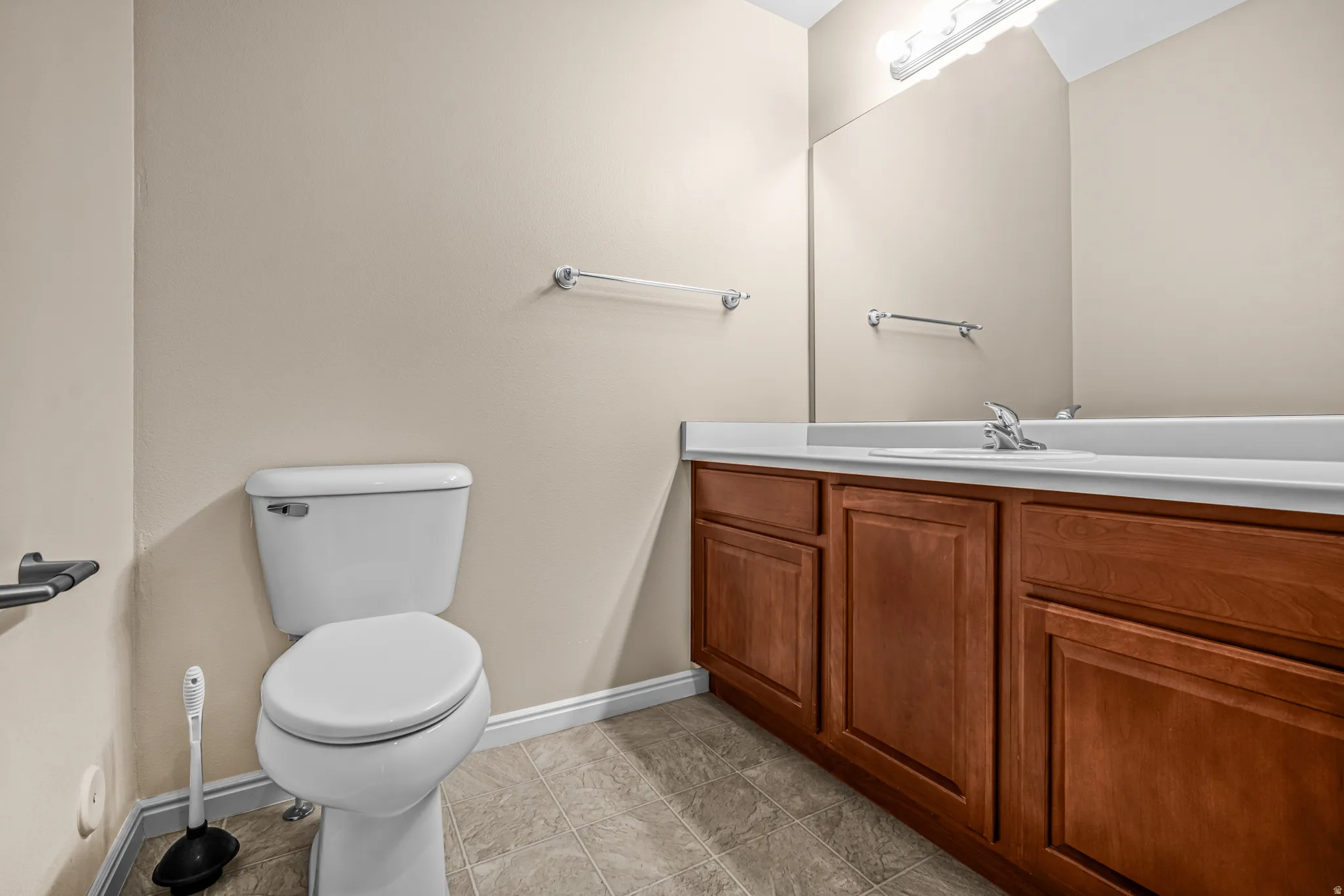 Bathroom featuring a wood-finish vanity with a white countertop and integrated sink, a large wall-mounted mirror