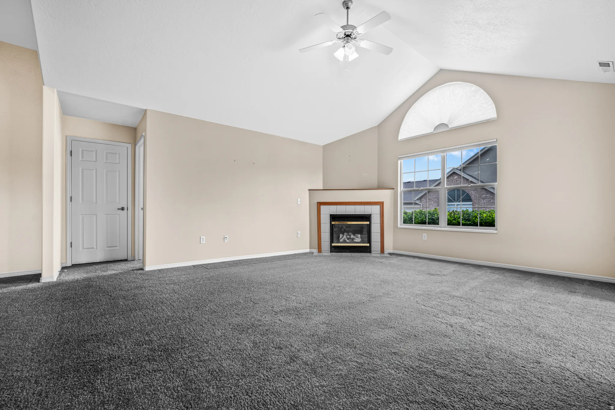 Spacious room featuring vaulted ceilings, a ceiling fan and a fireplace
