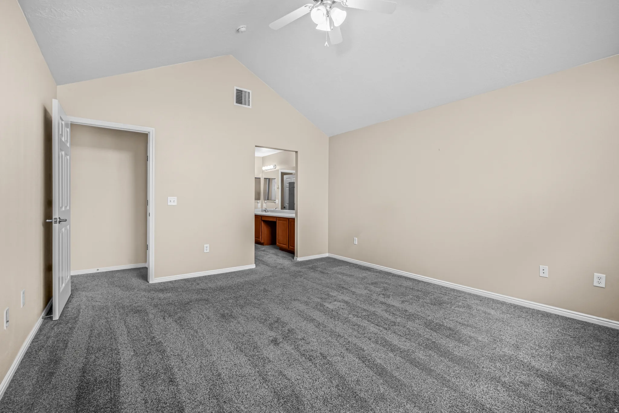 Spacious room featuring vaulted ceilings, neutral-toned walls