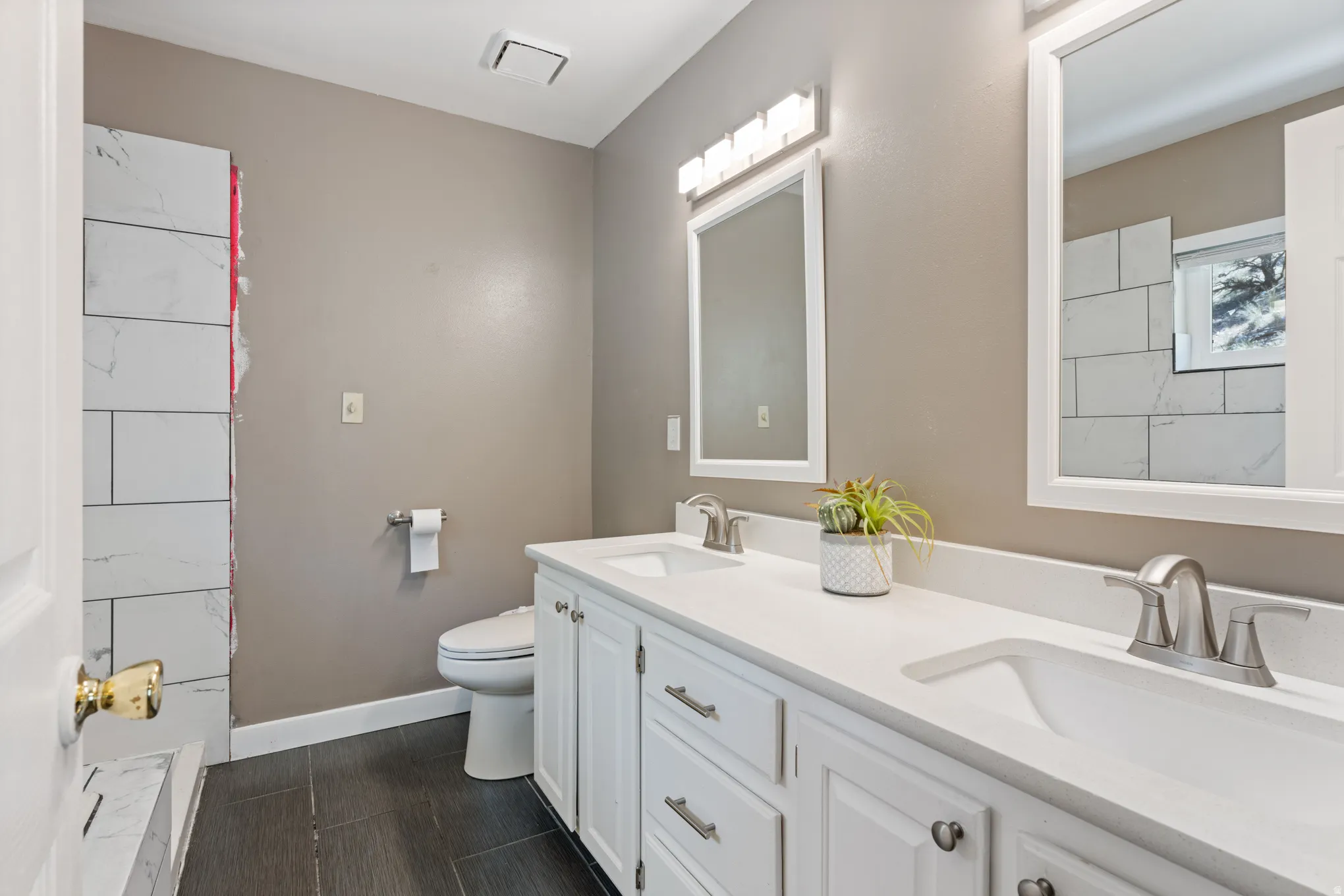 Dual vanity featuring white cabinetry, integrated sinks, brushed nickel fixtures, and a coordinating framed mirror