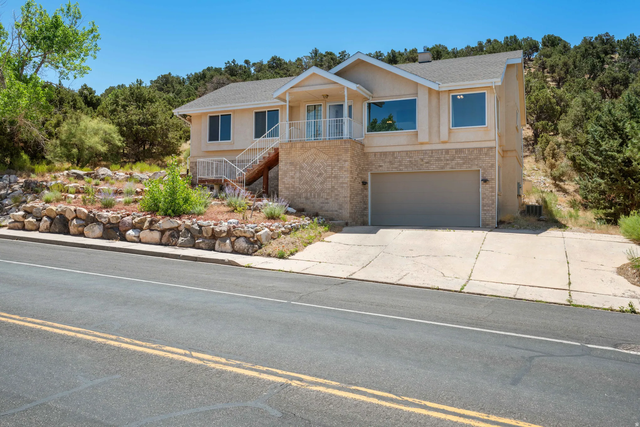 Two-story residence featuring a multi-tone exterior finish, a two-car garage with a panel door, and a front balcony with a white railing