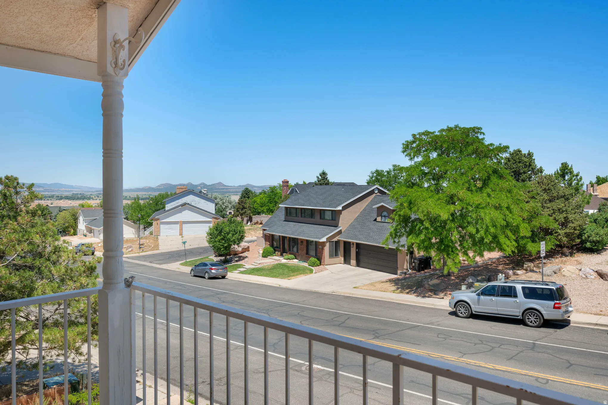 Balcony with white spindle railing overlooking a residential street