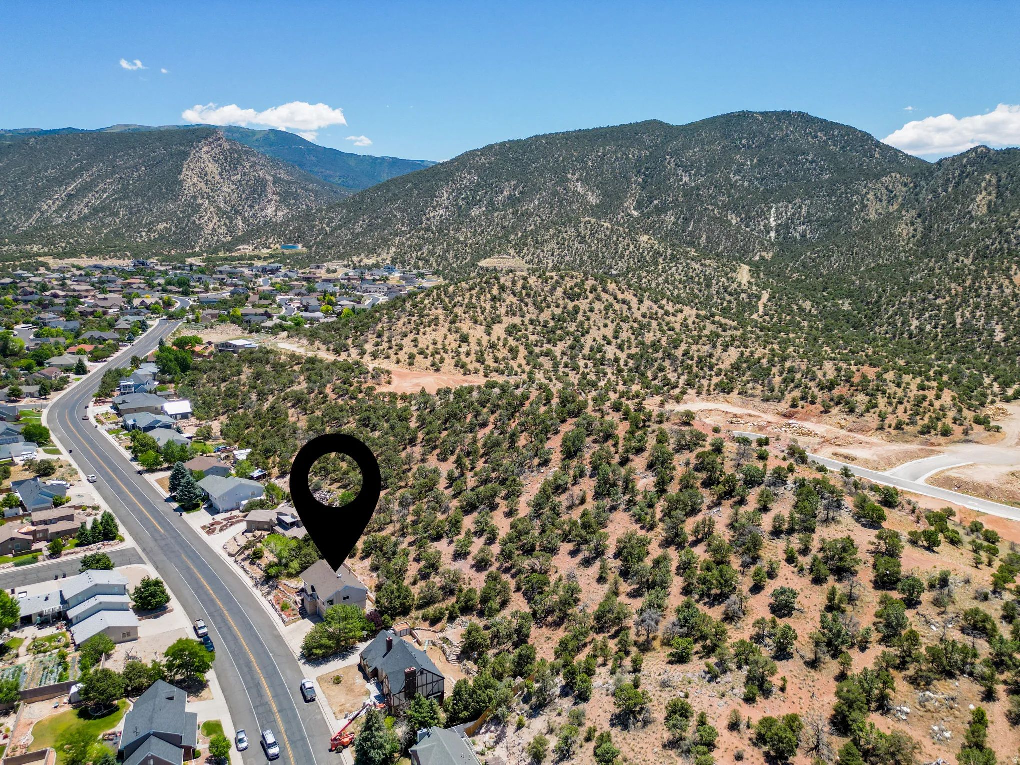Aerial perspective showcasing a property situated along a paved road with surrounding residential structures