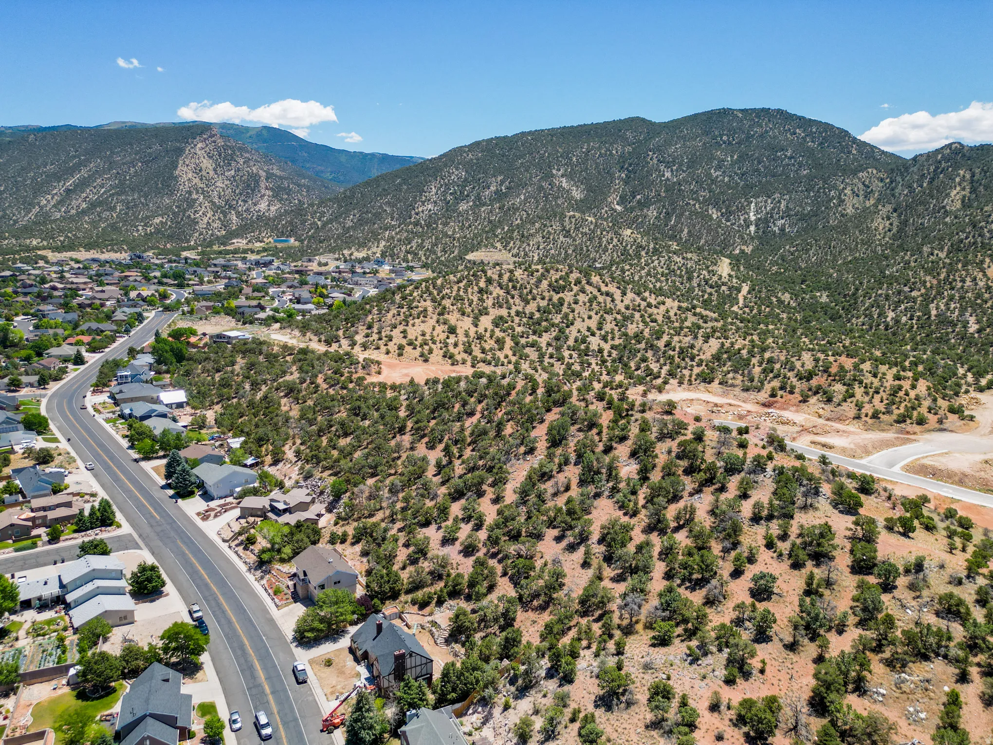 Expansive land parcel featuring natural desert vegetation, a winding paved road, and distant mountain backdrops