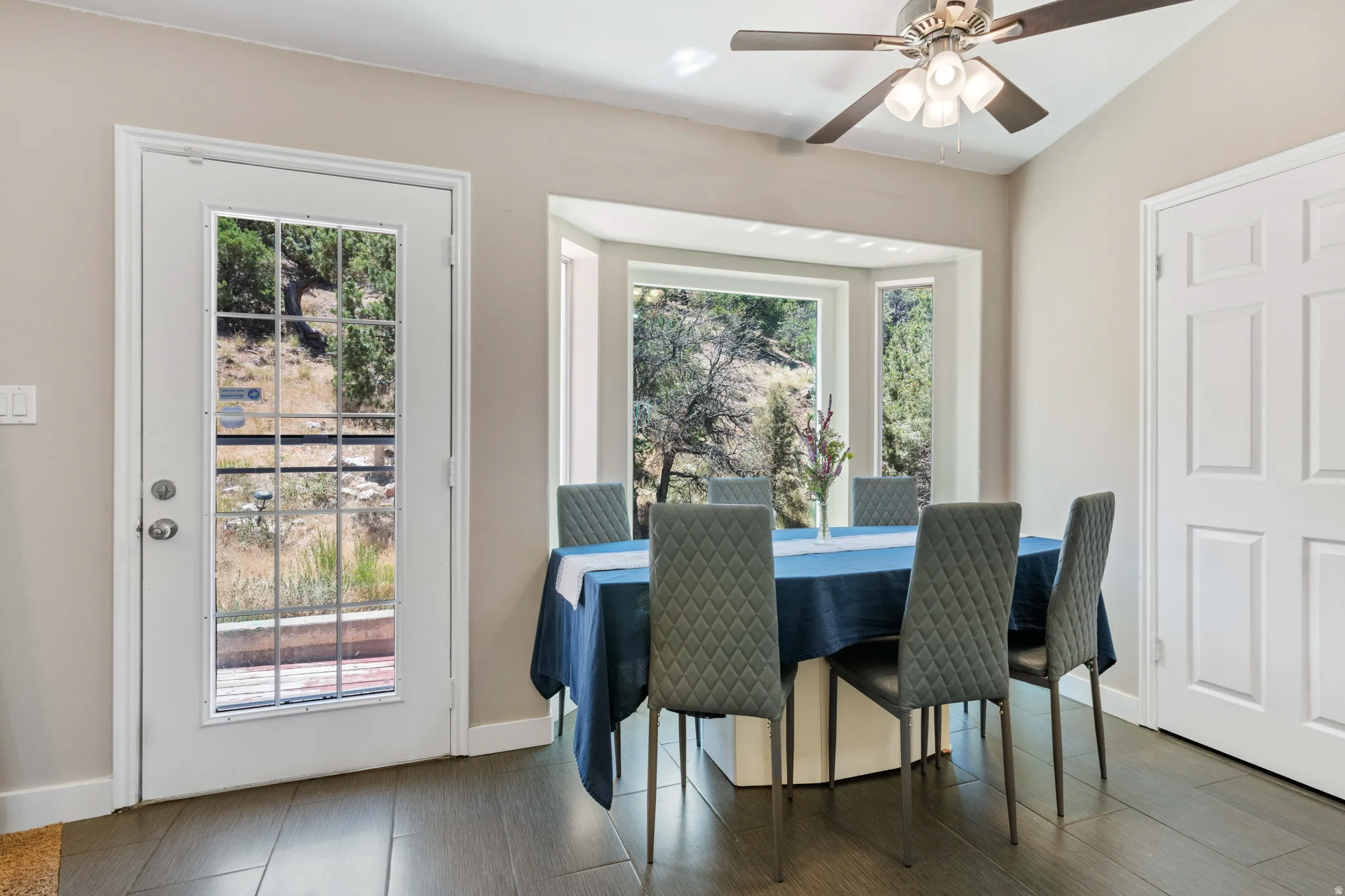 Dining area with wood-finish tile flooring, a multi-pane glass panel door, and a bay window