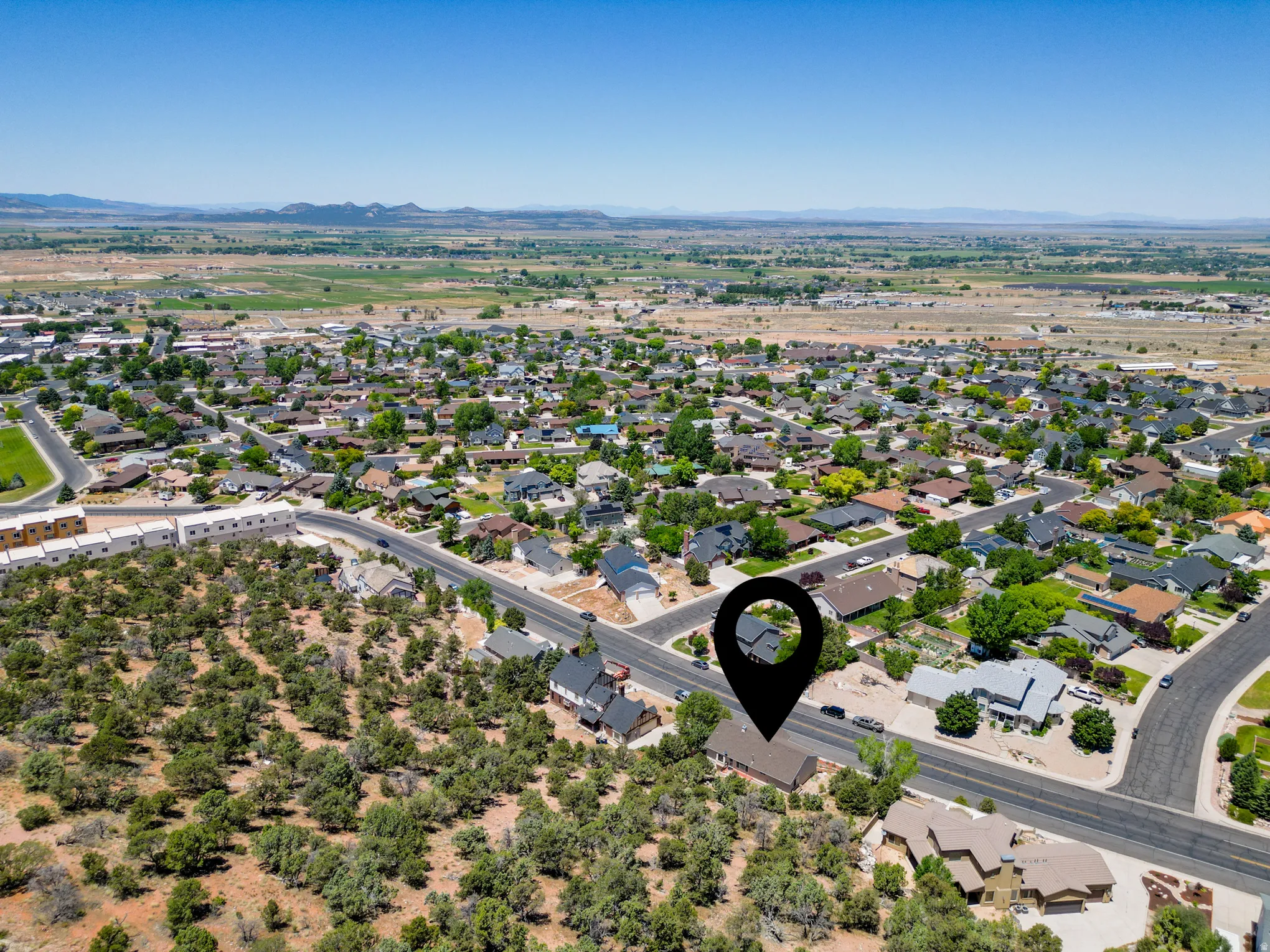 Aerial perspective showcasing a residential neighborhood with a mix of single-family homes and undeveloped, tree-covered land