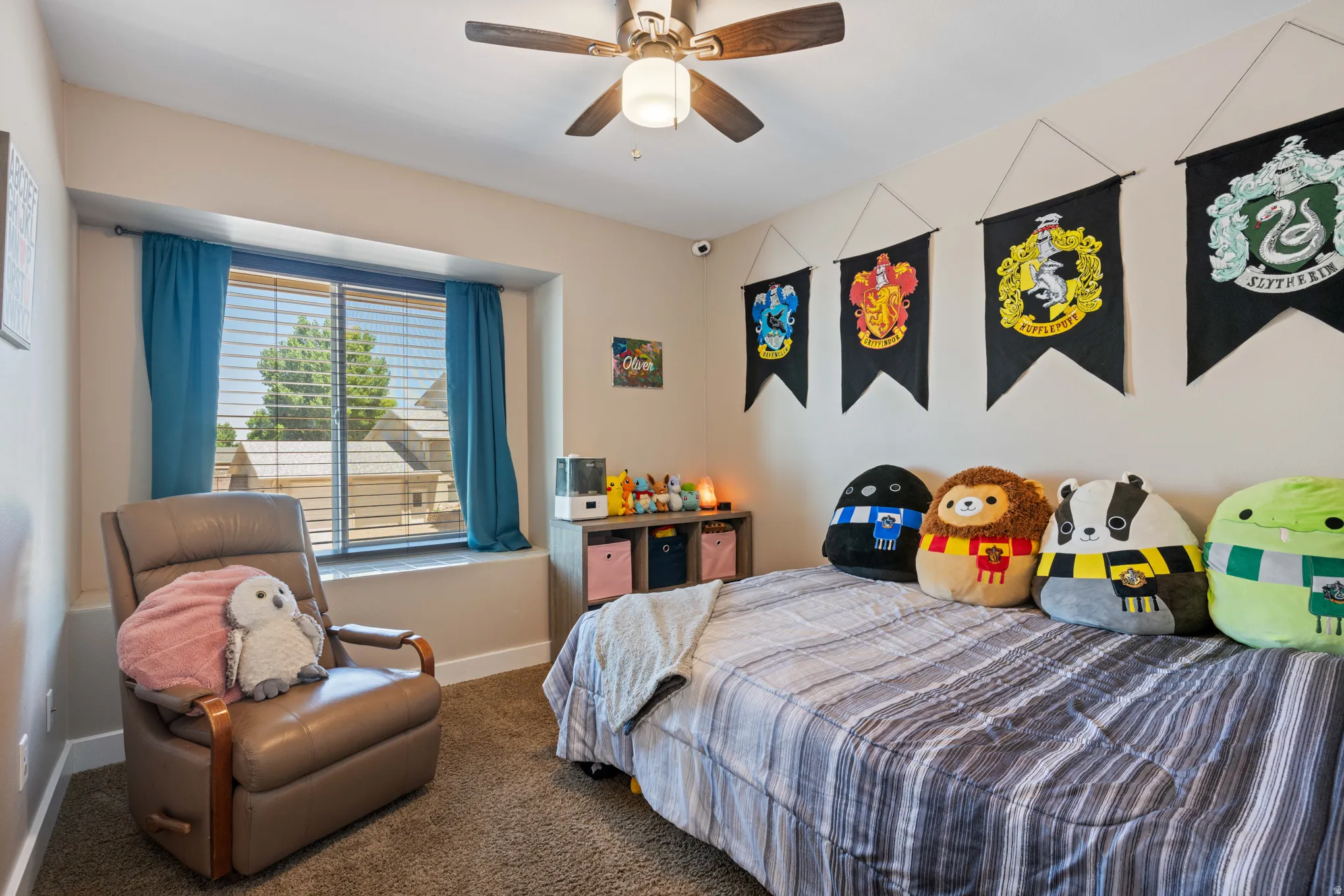 Bedroom featuring a bay window with blinds, a ceiling fan with light fixture, carpet flooring, and neutral wall paint
