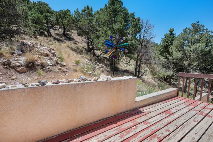 Outdoor wooden deck with a wooden railing and a stucco wall