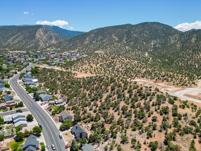 Expansive land parcel featuring natural desert vegetation, a winding paved road, and distant mountain backdrops