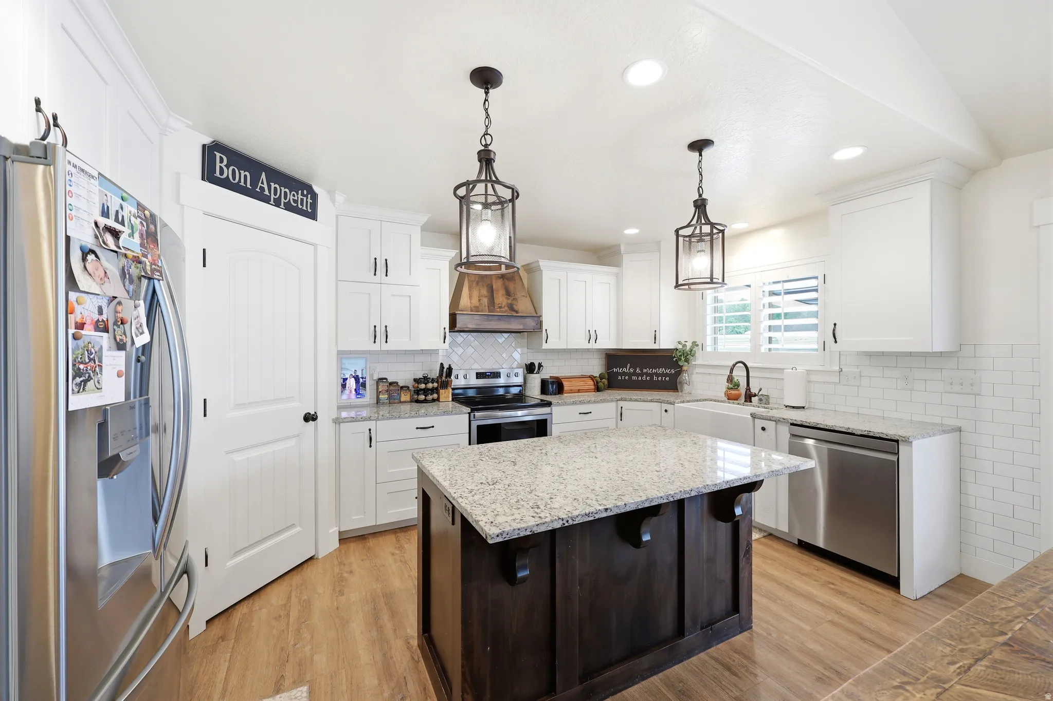 Central kitchen island with a light granite countertop and dark wood base, complemented by wood-finish flooring