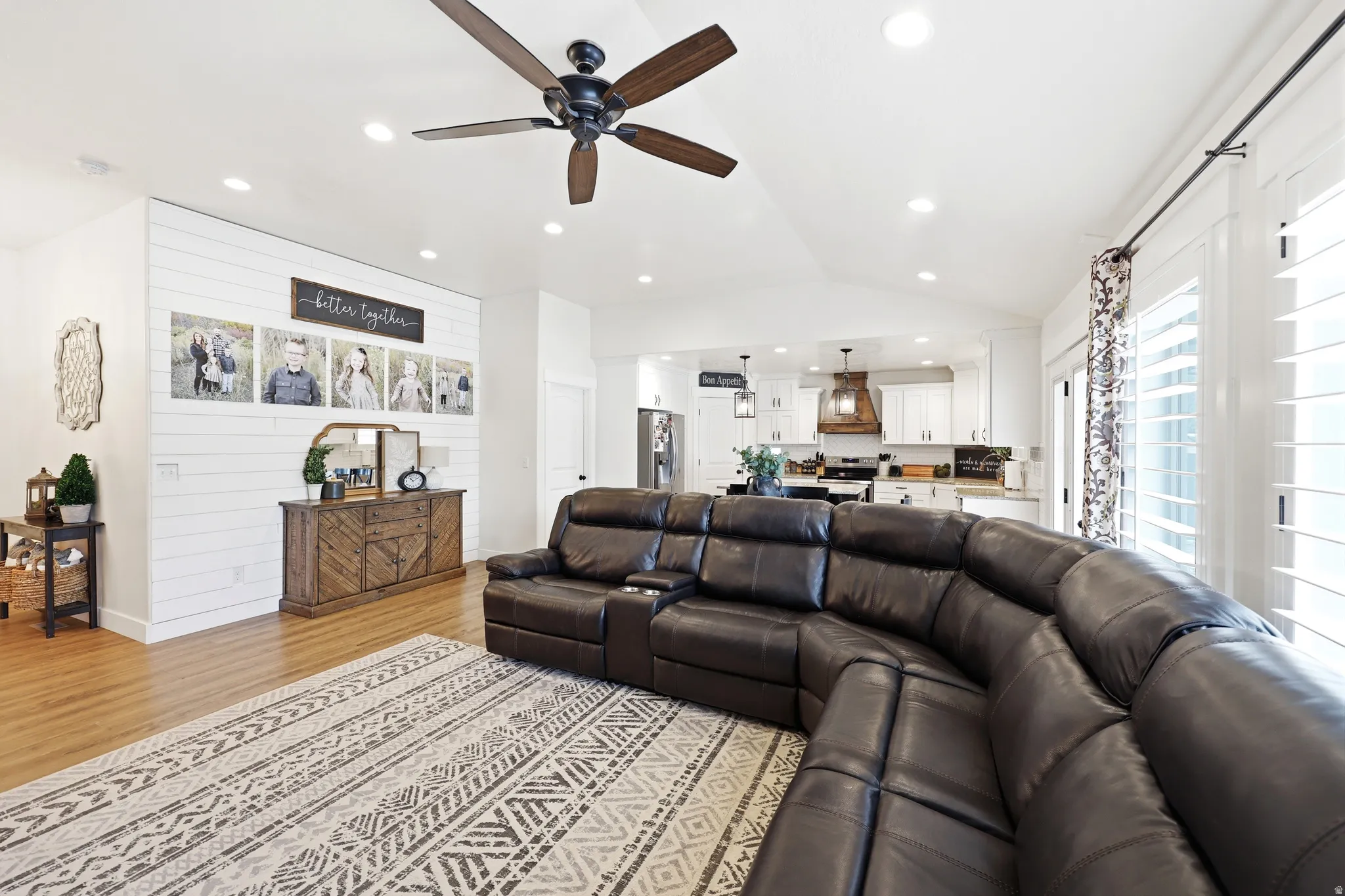 Open-concept living area featuring a vaulted ceiling with a ceiling fan, recessed lighting, and wood-finish flooring