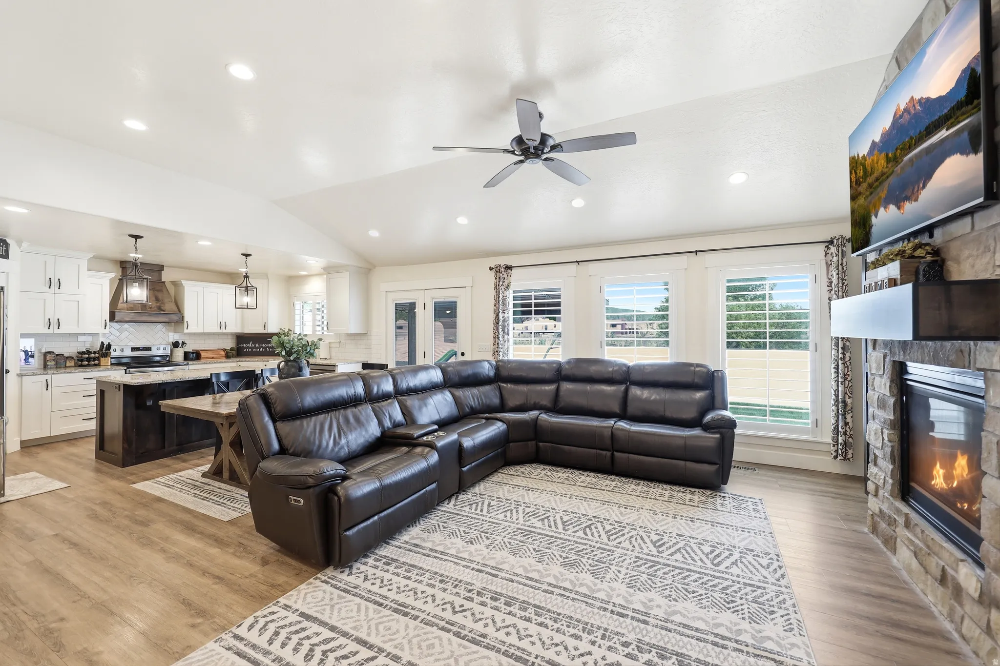Open-concept living space featuring wood-finish flooring, vaulted ceilings, and recessed lighting