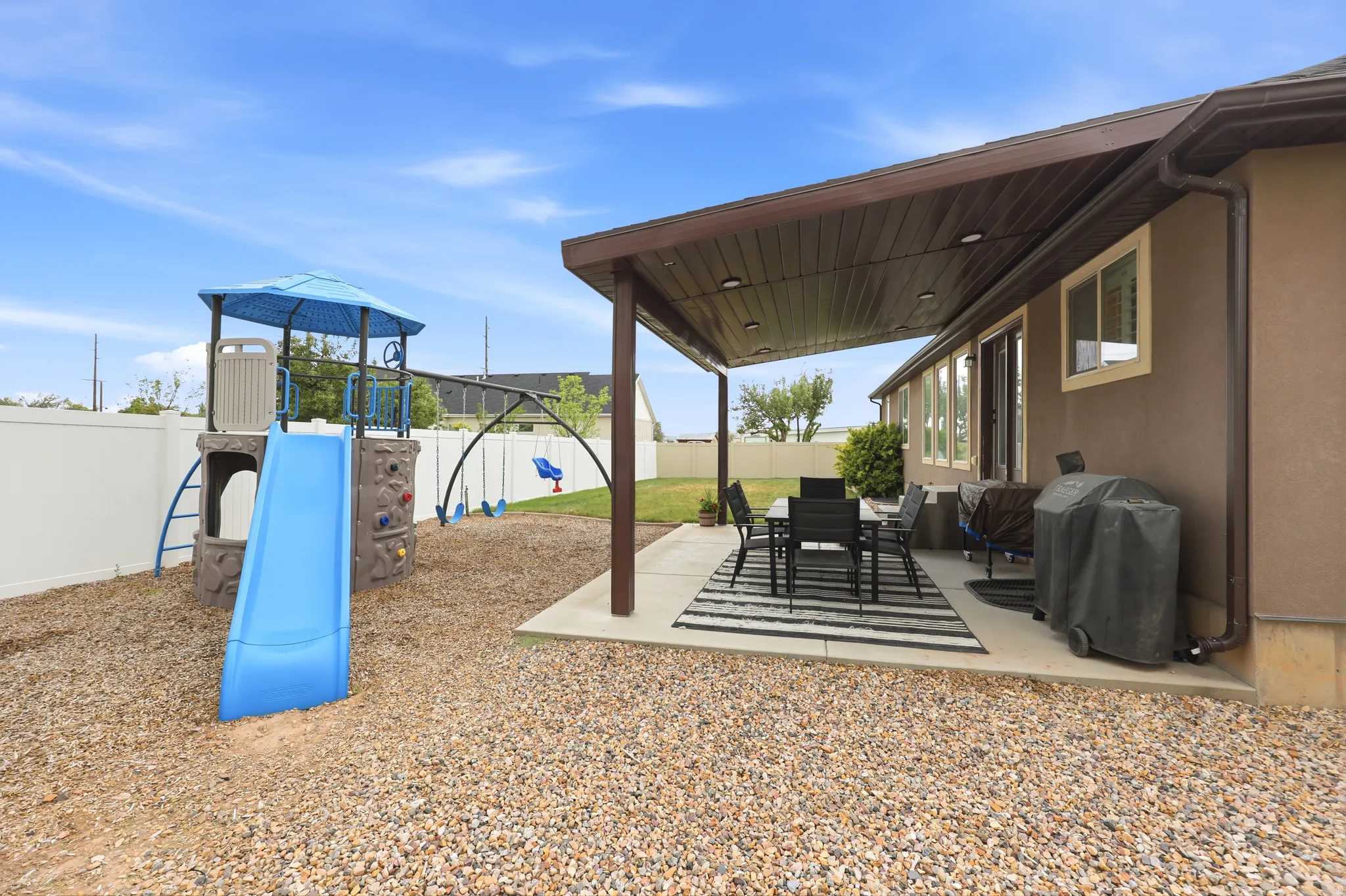 Covered patio area with recessed lighting, stucco exterior, multiple windows, and a white privacy fence