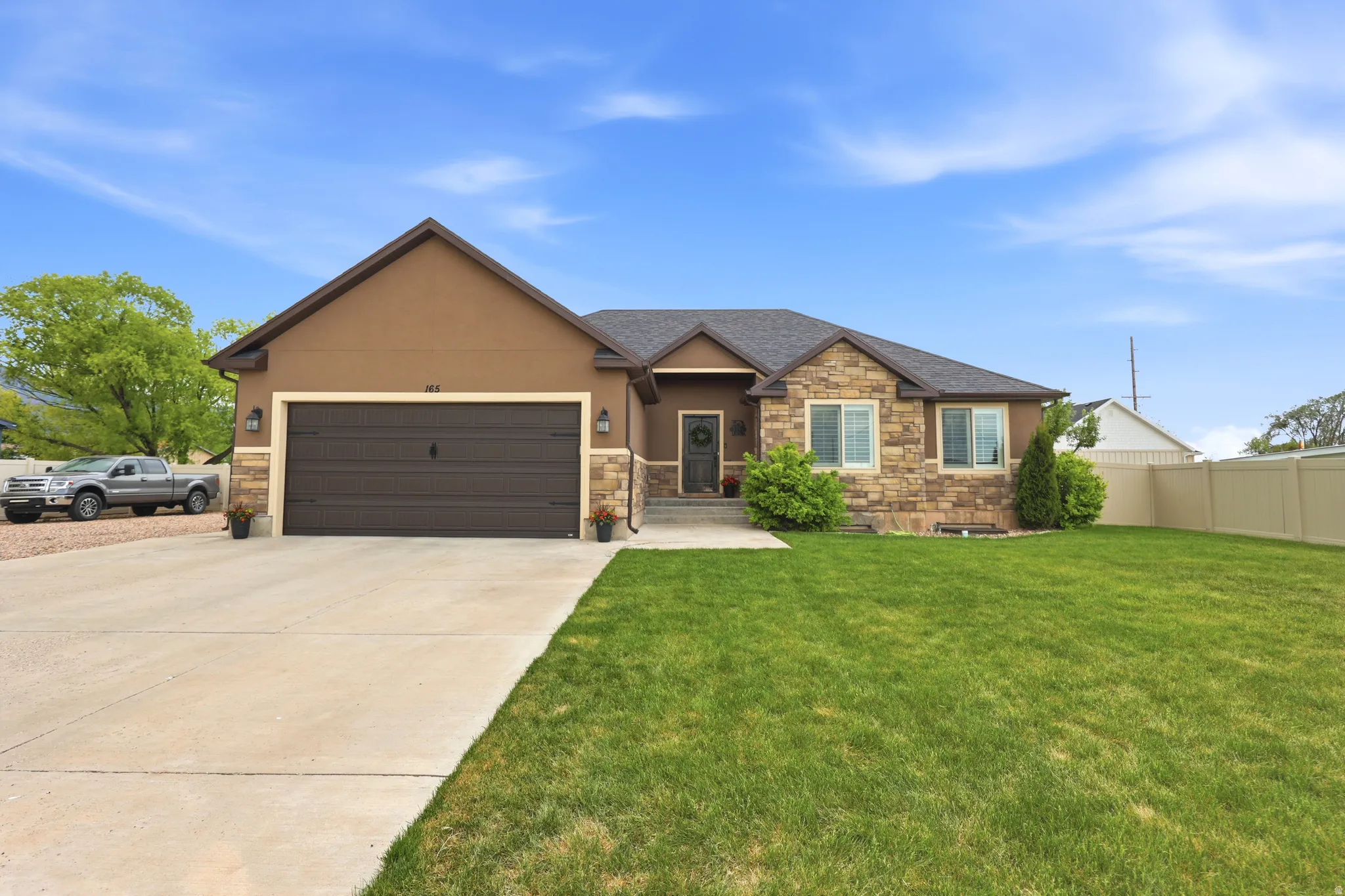 Brown stucco exterior with stone accents and a dark brown garage door