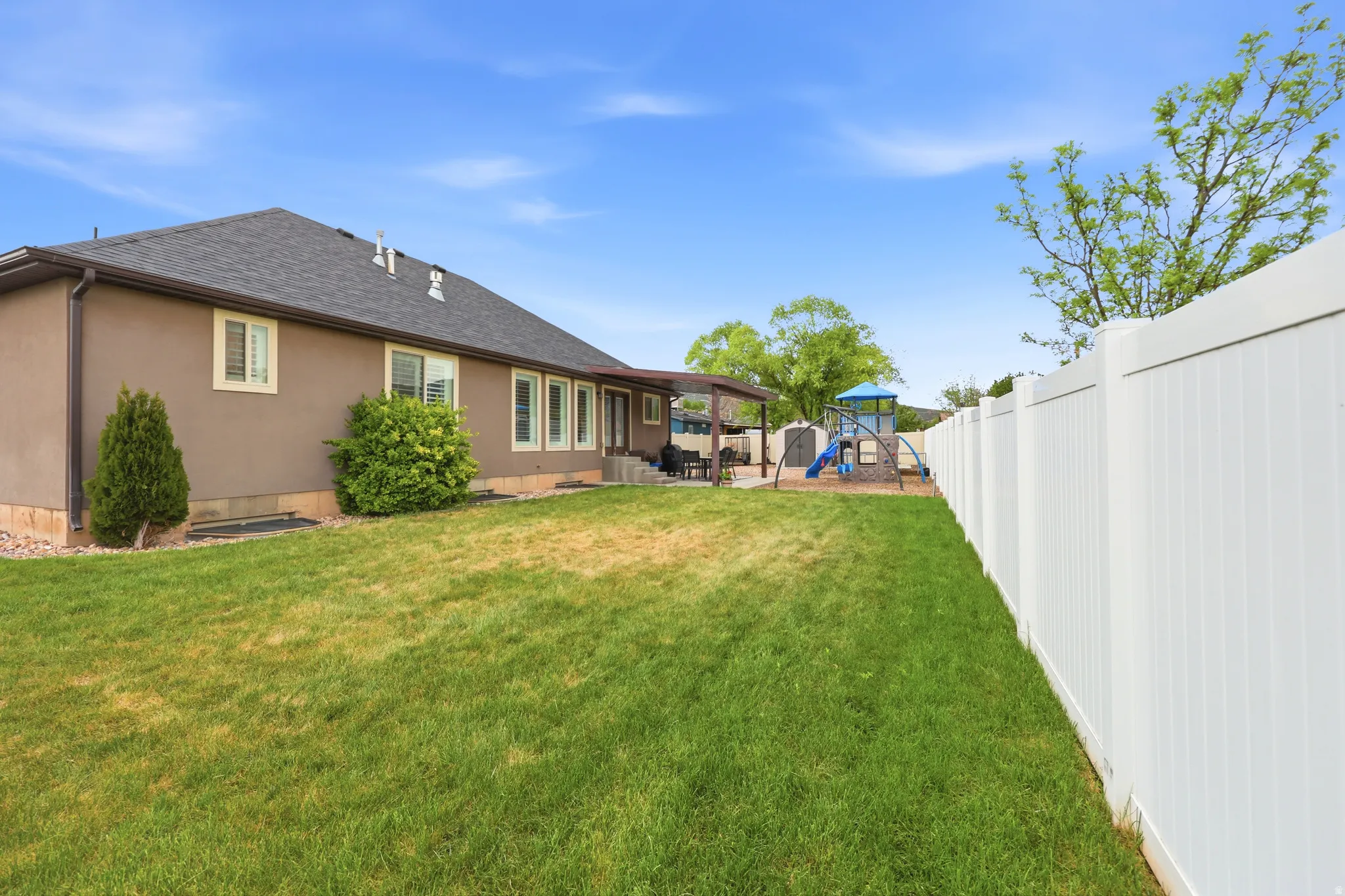 Expansive backyard featuring a manicured lawn and a full vinyl fence