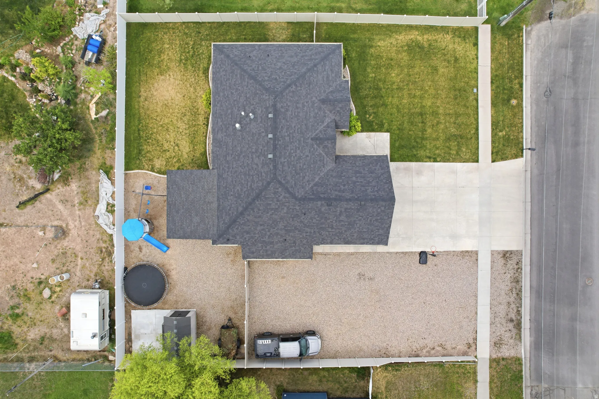 Property featuring a dark shingle roof, concrete driveway, and gravel parking area