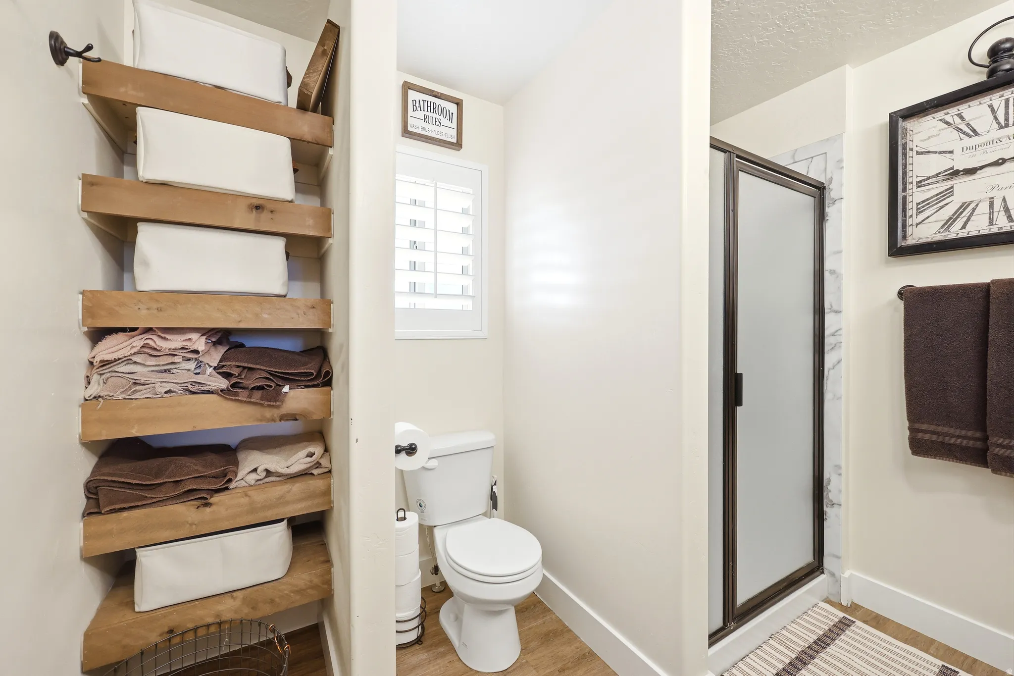 Bathroom with a standing shower featuring a frosted glass door and white marble-style surround
