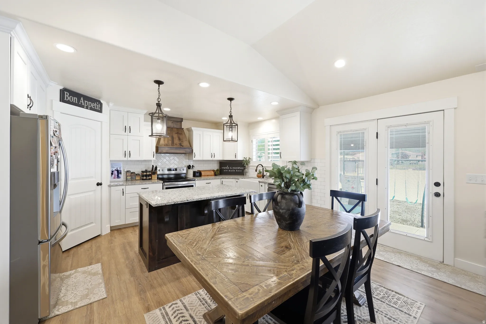Kitchen with vaulted ceiling, white cabinetry, and wood-finish flooring