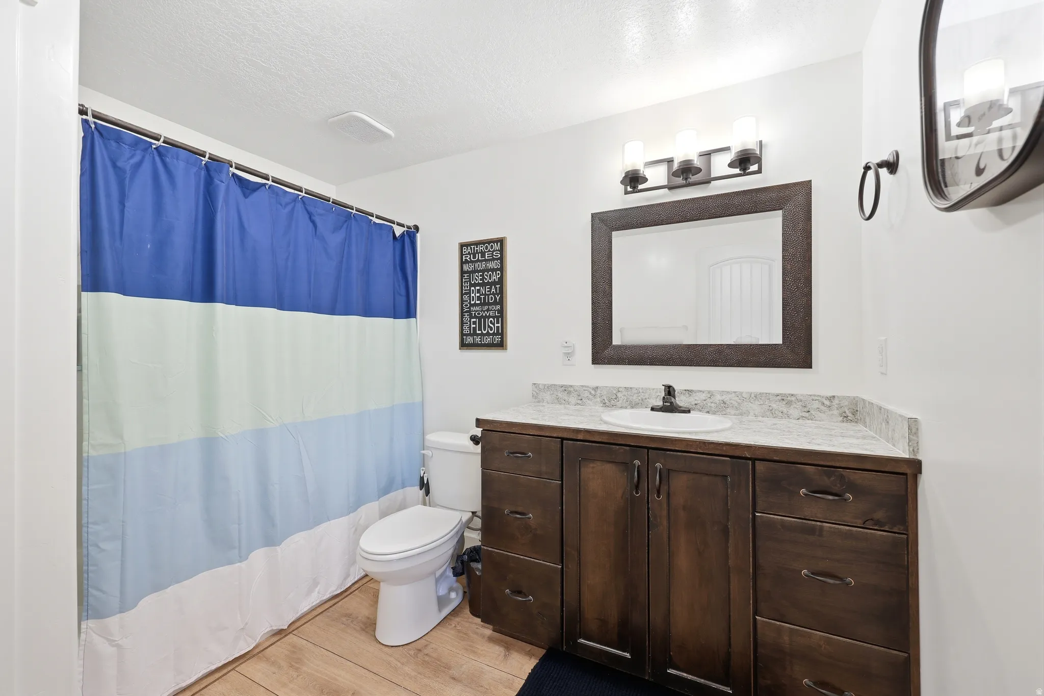 Bathroom featuring a dark wood vanity with ample storage, a white undermount sink, and a light-colored countertop