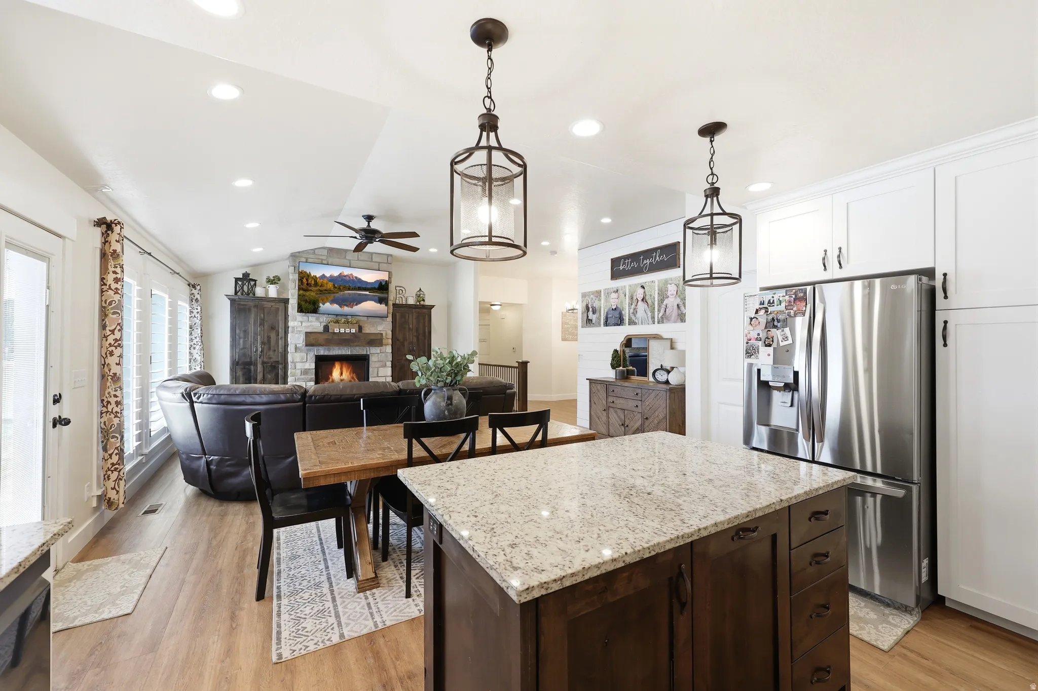Kitchen featuring a granite-topped island with dark wood cabinetry, white upper cabinets, and a stainless steel refrigerator