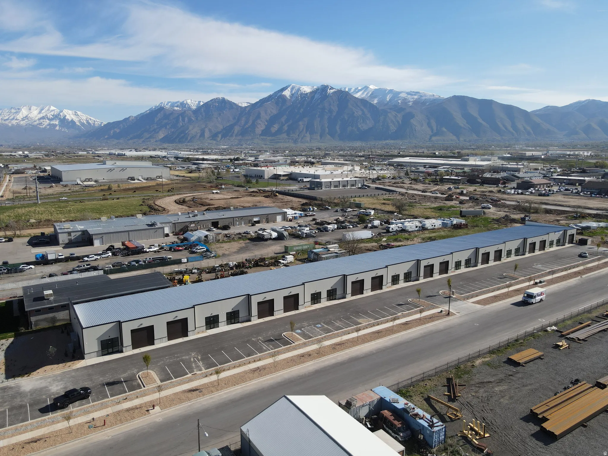 Industrial complex featuring multiple units with roll-up doors, paved parking areas, and a visible roadway