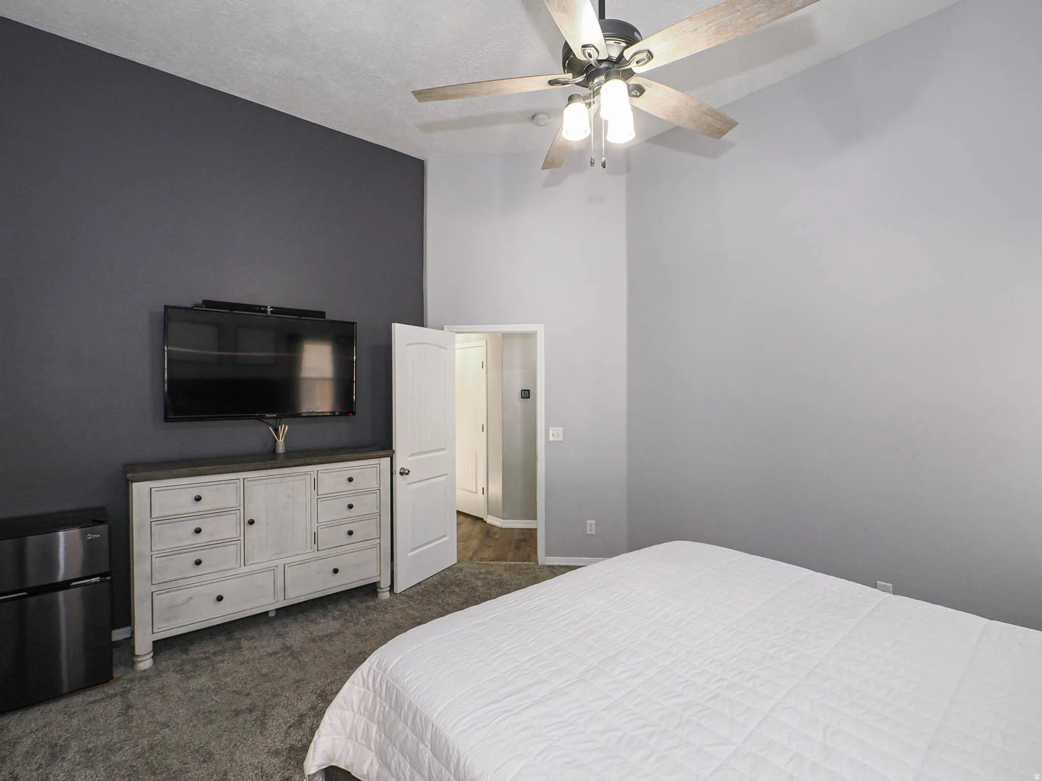 Interior room featuring vaulted ceilings, a ceiling fan with light fixture, and a two-tone wall treatment with a dark accent wall