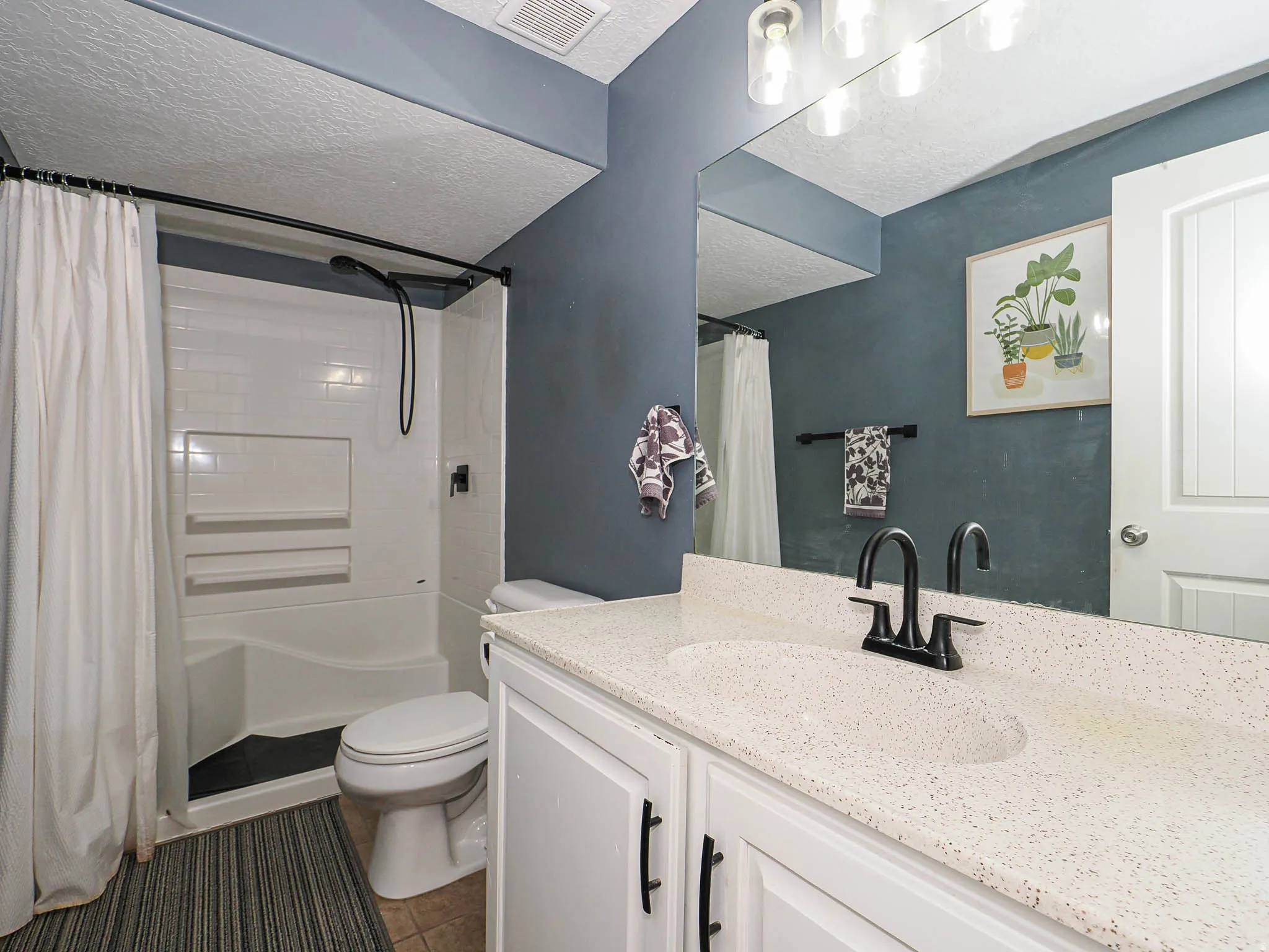 Bathroom featuring a white vanity with a speckled countertop, integrated sink, and matte black faucet